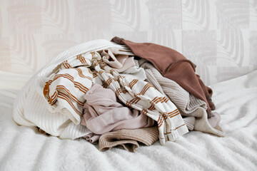 Pile of unfolded dirty clothes for laundry on the bed. Heap of used clothes for donation and...