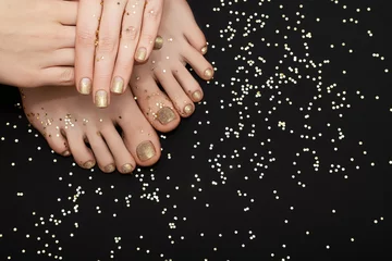 Zelfklevend Fotobehang Female hands with golden nail design. Glitter gold nail polish pedicure. Female hands and feet with golden stars on black background. Copy space. © devmarya