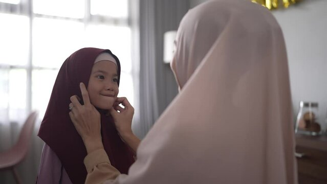 muslim mother fixing her dauhgter headscarf on ramadan