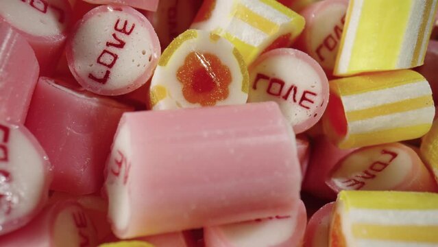 Colored striped caramel candies assorted, rotating shot. Mix of pink and yellow lollipops close up. Sweet sugar dessert. Candy Shop. Festive background. Slow motion ready, 4K at 59.94fps.