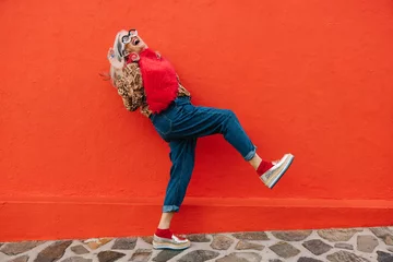 Foto auf Alu-Dibond Excited senior woman dancing and having fun against a red wall © Jacob Lund