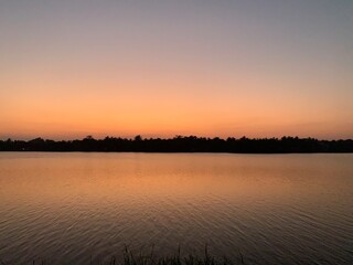 Naklejka premium Sun ray Sunset lake picture . Beautiful scenery and Sunset on a lake with a ray of sunlight reflecting on the water.