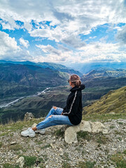 Naklejka na ściany i meble A girl on the background of a breathtaking view of the mountains in Dagestan, Caucasus. Russia 2021