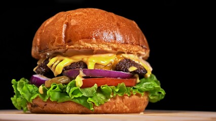 Craft burger is cooking on black background in black food gloves. Consist: sauce, lettuce, tomato,...