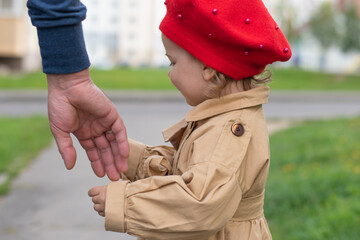 The concept of protection against child abduction. The kid stands next to a man who holds out his hand to him.