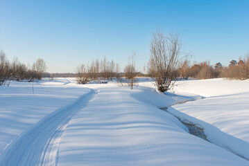 Snowmobile road along the frozen river