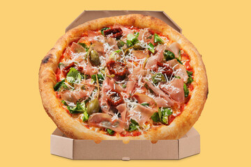 italian pizza with prosciutto and sun-dried tomatoes, in an open box, on a yellow background, delivery concept