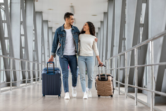 Trip Together. Happy Young Arab Spouses Walking With Luggage At Airport Terminal,