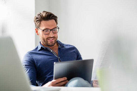 Businessman wearing eyeglasses using tablet PC at office
