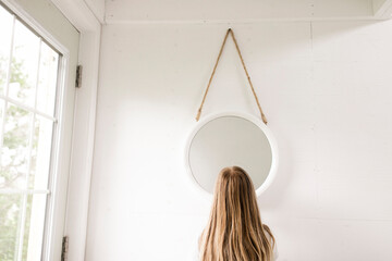 Blond girl standing in front of mirror at home