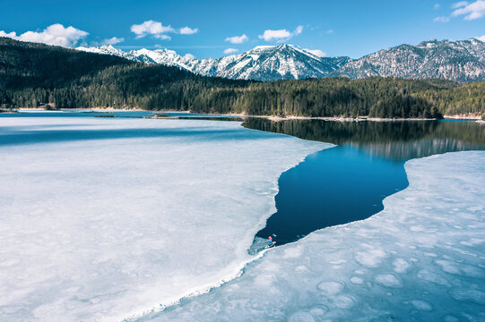Germany, Bavaria, Aerial view of lone man paddleboarding between ice floes in Eibsee lake