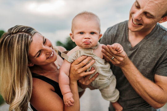 Happy parents with cute baby son making funny face