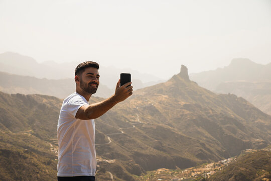 Smiling man taking selfie through mobile phone at Degollada de Becerra, Spain