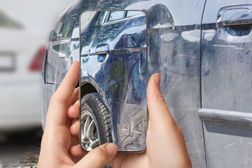 A girl takes pictures on a smartphone of car damage at the scene of an accident for insurance...