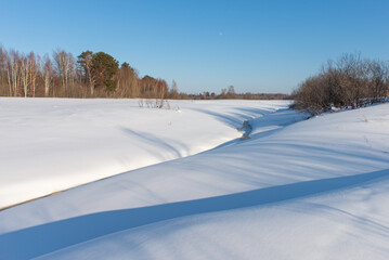 Frozen small river. Winter landscape against the blue sky