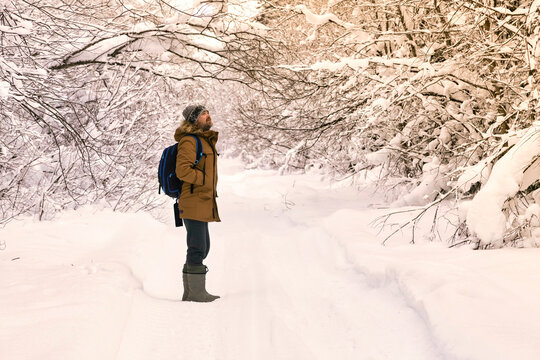 Male hiker standing in middle of snow covered forest road
