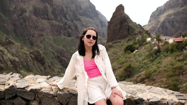 Portrait of beautiful young woman in sunglasses overlooking glorious mountains landscape 