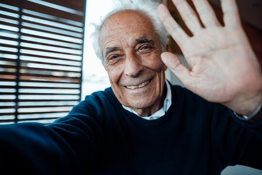 Smiling senior man with white hair gesturing at houseboat