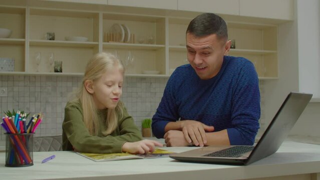Joyful handsome hearing impaired father and engrossed in reading lovely preadolescent daughter with communication disorder talking, discussing interesting comic book using sign language indoors.