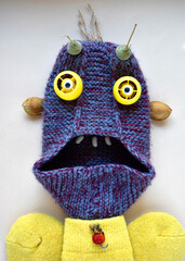 funny cute monster made of a knitted slipper with eyes made of plastic caps in a yellow sweater made of warm socks