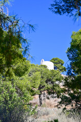 Low angle view of La Magdalena Hermitage access among Pine trees on a sunny day and blue sky