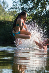 young girl jumping into the river in the summer on a hot day