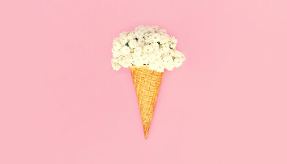 Ice cream cone with flowers on colorful pink background, top view, flat lay