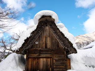 Hida, Japan - February 18, 2022 : Icicle-hung eaves of thatched roof or gassho-zukuri. 
