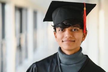 Portrait of indian handsome male graduate in graduation robe and blured background.