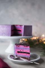 Christmas lights after cake. New Year cheesecake with lavender and blueberry. Slice of mousse cake, cheesecake with fresh berry on a white  background