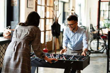 Colleagues having fun at work. Businessman and businesswoman playing table soccer..