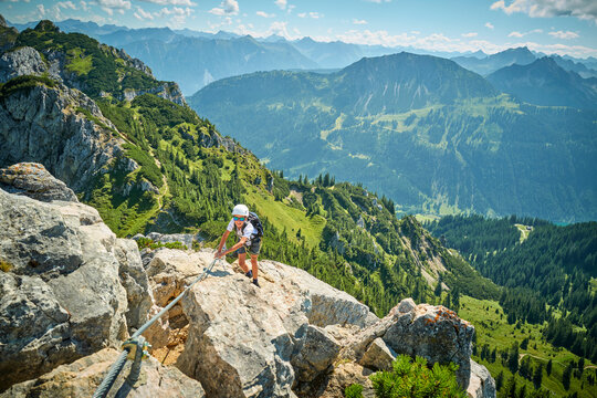 Boy climbing rock on sunny day
