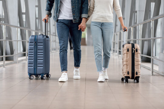 Travelling Concept. Cropped Shot Of Couple Walking With Luggage In Airport
