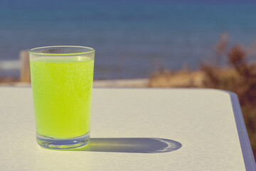 Citrus drink in glass on sea shore