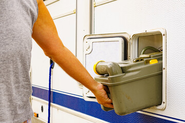 Man serving caravan, tank toilet cassette in dump station.