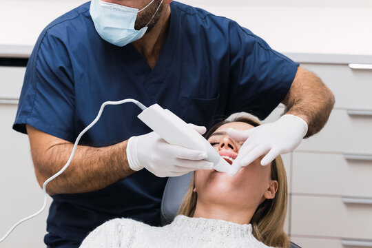 Dentist examining patient's teeth with intraoral scanner in clinic