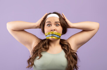 Frightened sad shocked plus size european young lady in sportswear with closed mouth wrapped...