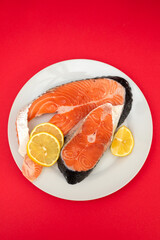 raw fresh salmon on ceramic plate on red