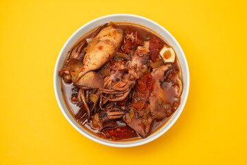 fresh tasty squid stew in white bowl on yellow