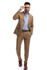 full body picture of sexy businessman looking away and fixing glasses