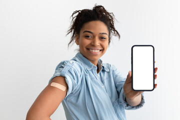 Naklejka premium Happy black lady showing plaster on arm and blank screen