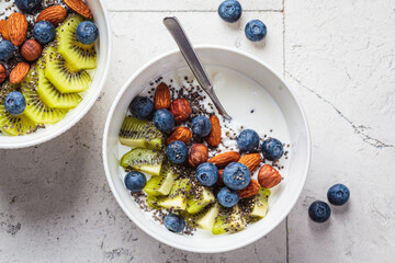 Breakfast cottage cheese with berries, nuts and chia seeds in white bowl.
