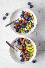 Breakfast cottage cheese with berries, nuts and chia seeds in white bowl.