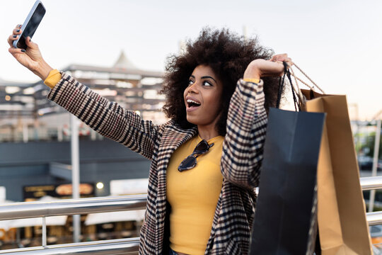 Happy woman with shopping bags taking selfie on smart phone