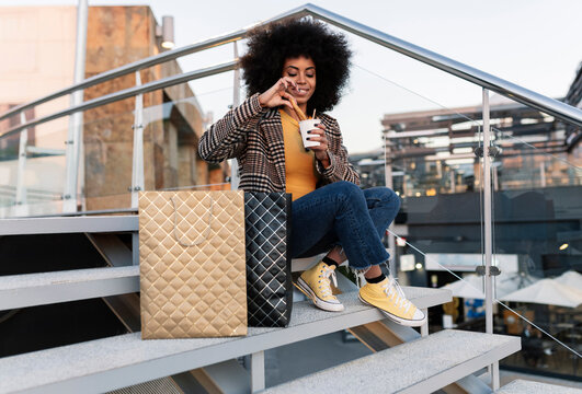Woman with shopping bags dipping churro in disposable cup