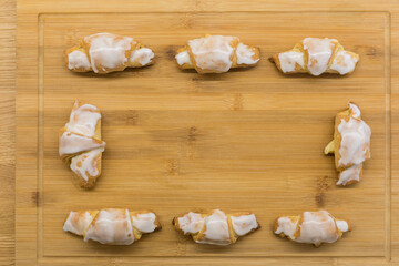 Homemade croissants with icing on a light board