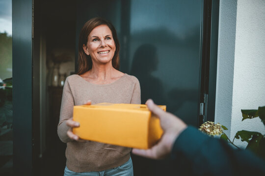 Happy woman receiving package from delivery person at doorway