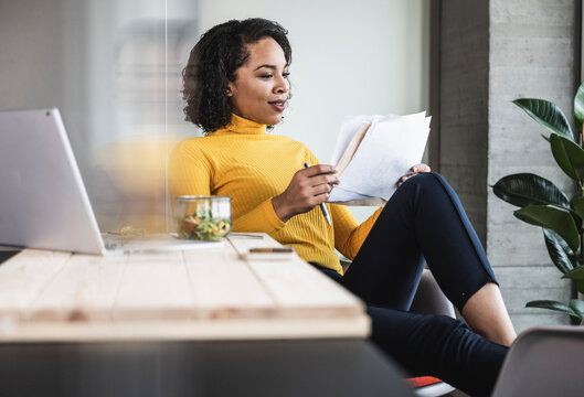 Young businesswoman reading paper document at work place