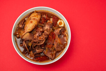 fresh tasty squid stew in white bowl on red