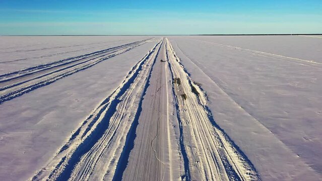 Aerial drone view of traffic on a winter road, cars driving on frozen sea ice